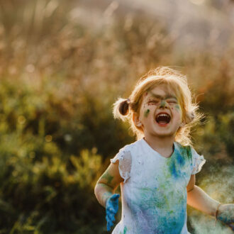 Kleines Mädchen ist mit Farbe bedeckt und lacht