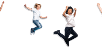 Vier Kinder springen in die Luft und lachen in die Kamera