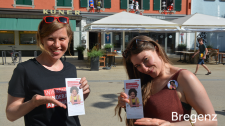 Mitarbeiterinnen halten Flyer in den Händen und lächeln in die Kamera, im unteren rechten Bereich des Bildes steht "Bregenz"