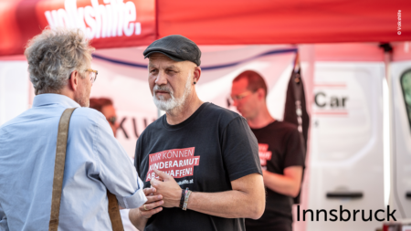 Erich Fenninger redet mit einem Besucher, im unteren rechten Abschnitt des Bildes steht "Innsbruck"