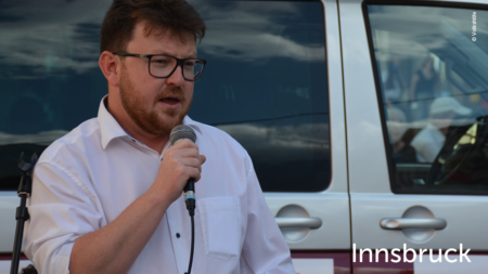 Mann redet ins Mikrofon, im unteren rechten Bereich des Bildes steht "Innsbruck"