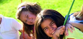 Vier Kinder sitzen auf einer Schaukel und lächeln in die Kamera