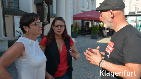 Erich Fenninger unterhält sich mit zwei Frauen, im unteren rechten Abschnitt des Bildes steht "Klagenfurt"