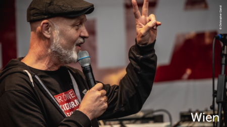 Erich Fenninger hält eine Rede, im unteren rechten Abschnitt des Bildes steht "Wien"