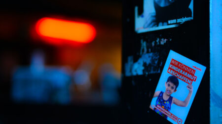 Volkshilfe Aufkleber klebt an der Wand, Aufschrift. "Wir können Kinderarmut abschaffen!"