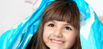 Mädchen hat Bettdecke über ihrem Kopf und lächelt breit