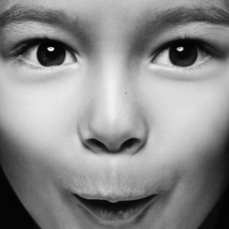 Portrait von Kind, welches aufgeregt in die Kamera schaut