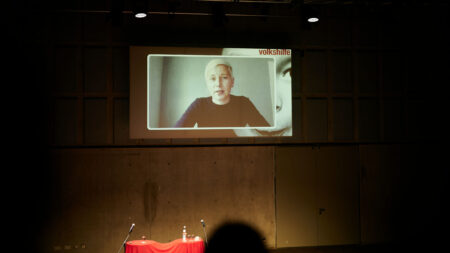 Thurid Blohm redet über einen Videocall der an die Wand projiziert wird