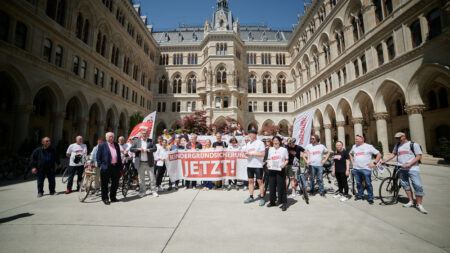 Gruppenfoto mit allen Beteiligten und Radfahrenden. In der Mitte wird ein großes Banner hochgehalten mit der Aufschrift: "Kindergrundsicherung Jetzt!"