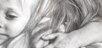 Zwei Kinder umarmen sich und schauen traurig aus