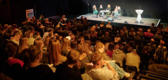 Blick auf das Publikum und eine Podiumsdiskussion beim Symposium gegen Kinderarmut der Volkshilfe.